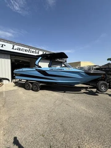 Slide: The Image of 2025 Centurion Fe25 boat in blue, parked on a trailer outside a dealership. - 2