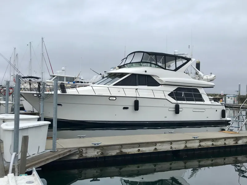 The Image of 1999 Bayliner 5288 Pilot House Motoryacht docked at a marina under cloudy skies. - 0
