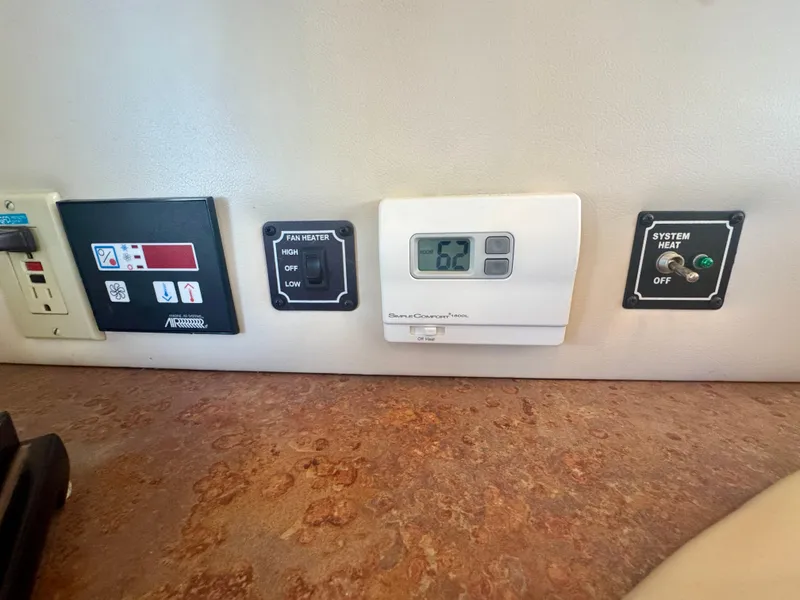 Slide: The Image of Control panel on 1999 Bayliner 5288 Pilot House Motoryacht dashboard, featuring thermostat and switches. - 24