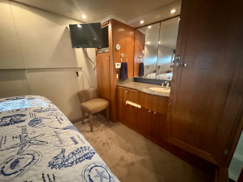 Slide: The Image of 1999 Bayliner 5288 Pilot House Motoryacht bedroom with TV, wooden cabinetry, and nautical-themed bedding. - 30