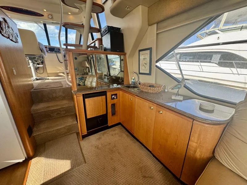 Slide: The Image of 1999 Bayliner 5288 Pilot House Motoryacht interior with wooden cabinetry and large windows. - 5