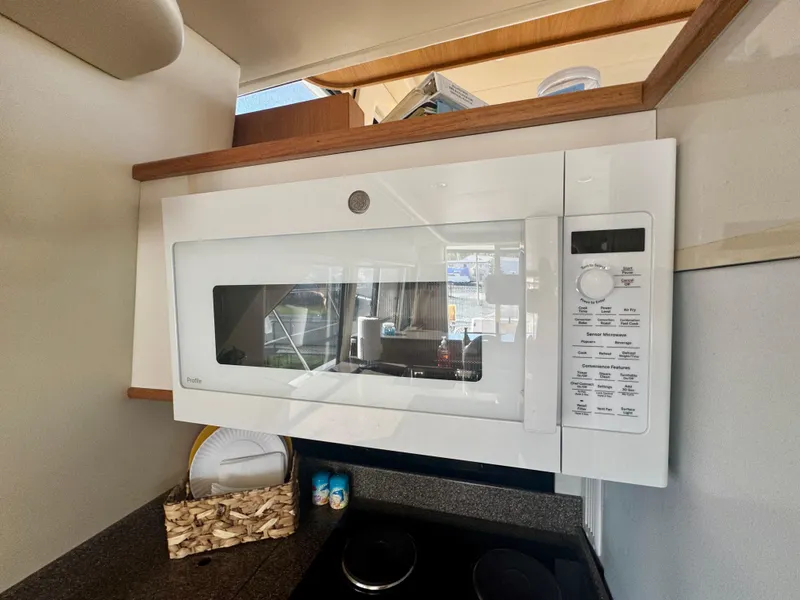 Slide: The Image of 1999 Bayliner 5288 Pilot House Motoryacht kitchen with white microwave and countertop accessories. - 8
