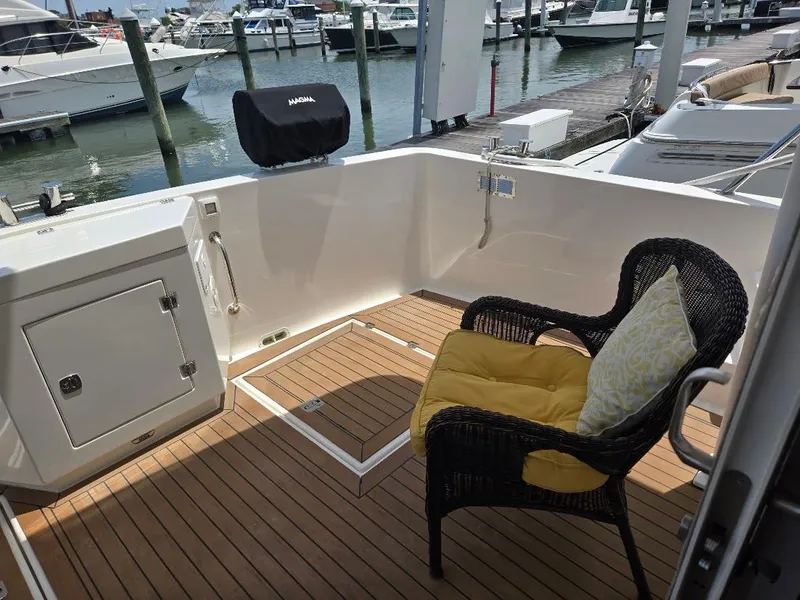 Slide: The Image of Outdoor seating area on 2010 American Tug 49 Limited yacht, featuring wicker chair and marina view. - 12