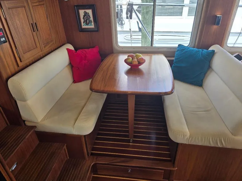 Slide: The Image of Cozy dining area in 2010 American Tug 49 Limited with cushioned seating and wooden table. - 19