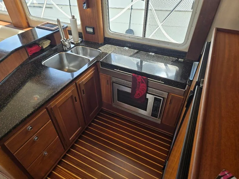 Slide: The Image of 2010 American Tug 49 Limited kitchen with wood cabinetry, dual sink, and microwave. - 20
