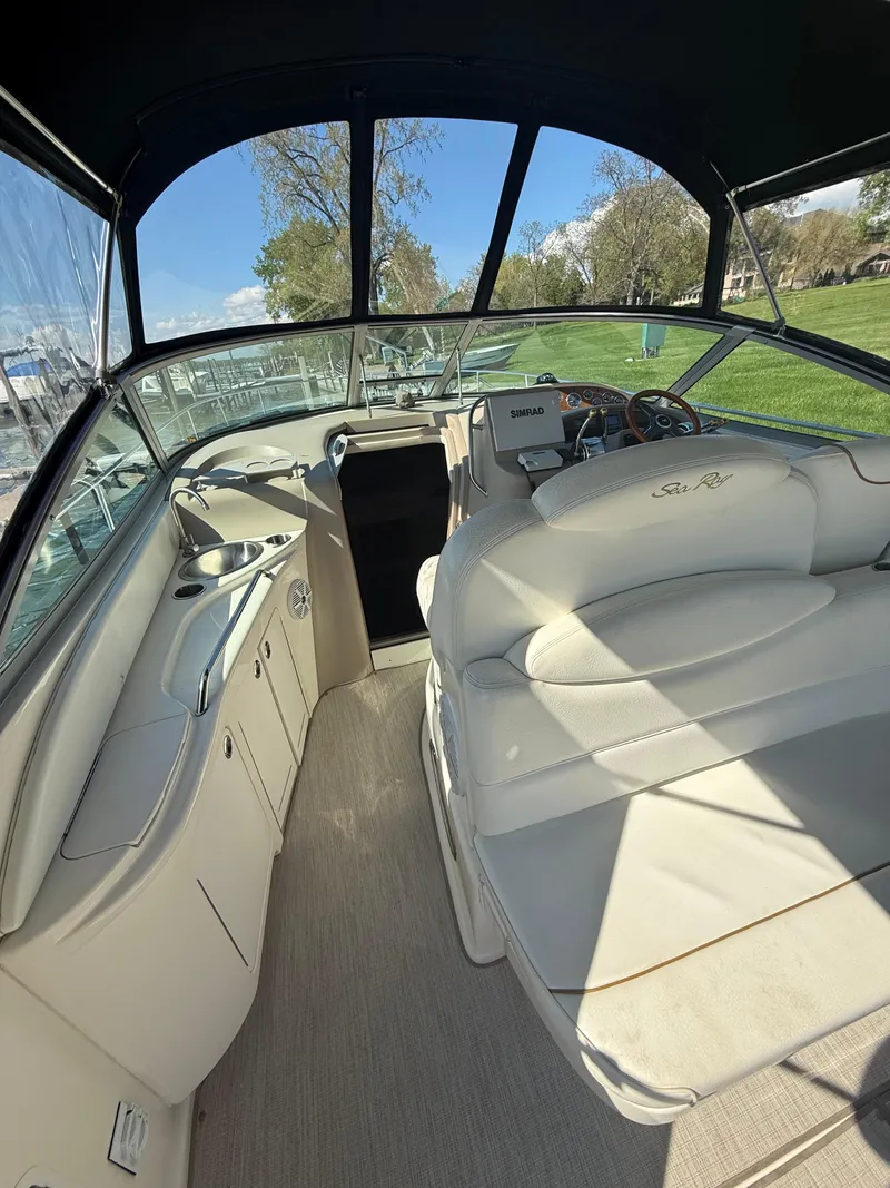 Slide: The Image of 1999 Sea Ray 340 Sundancer interior with plush seating and helm, under sunny skies. - 11