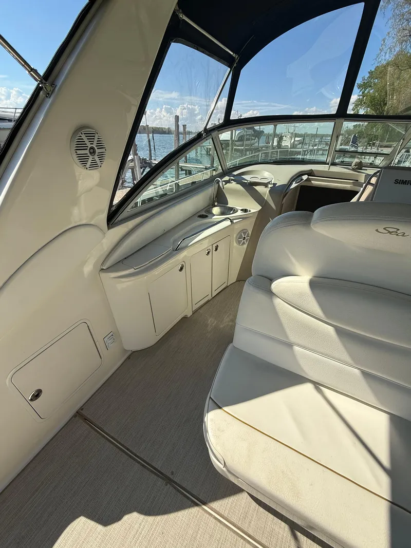 Slide: The Image of 1999 Sea Ray 340 Sundancer interior with beige seating and dashboard, docked at marina. - 15