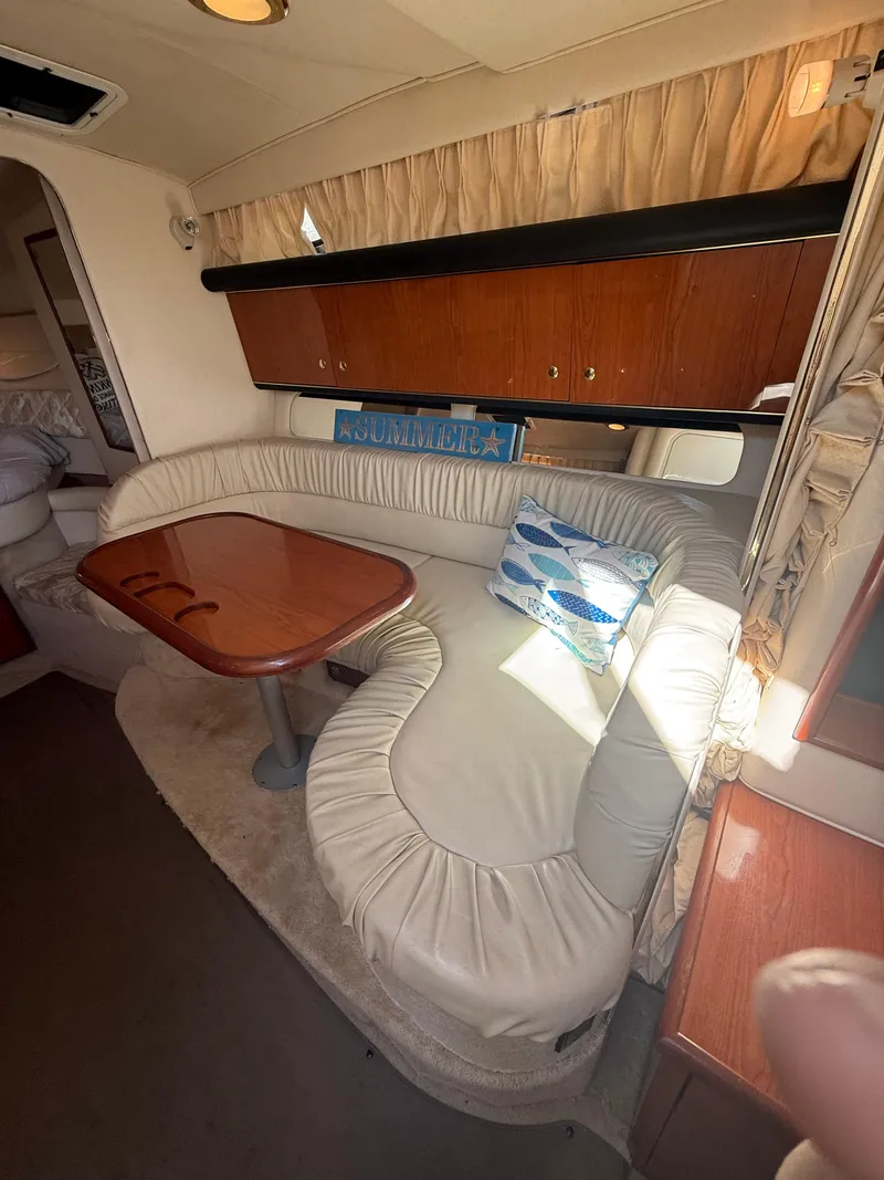 Slide: The Image of 1999 Sea Ray 340 Sundancer interior with curved seating and wooden table. - 25