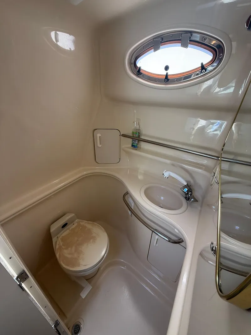 Slide: The Image of 1999 Sea Ray 340 Sundancer bathroom with toilet, sink, and porthole window. - 27