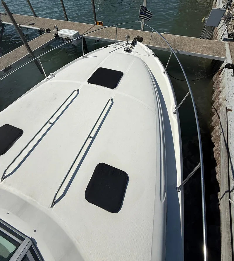 Slide: The Image of 1999 Sea Ray 340 Sundancer docked, showcasing sleek white deck and railings. - 5