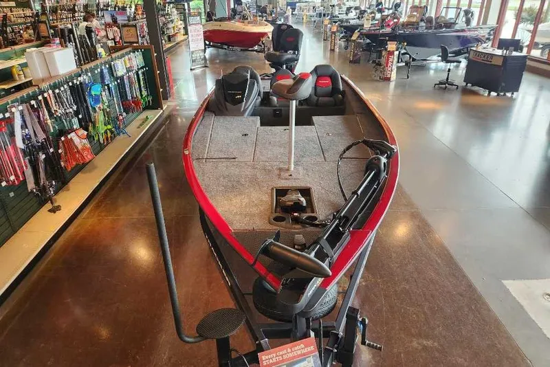 Slide: The Image of 2025 Tracker Savage 215 boat displayed in a showroom with fishing gear. - 2