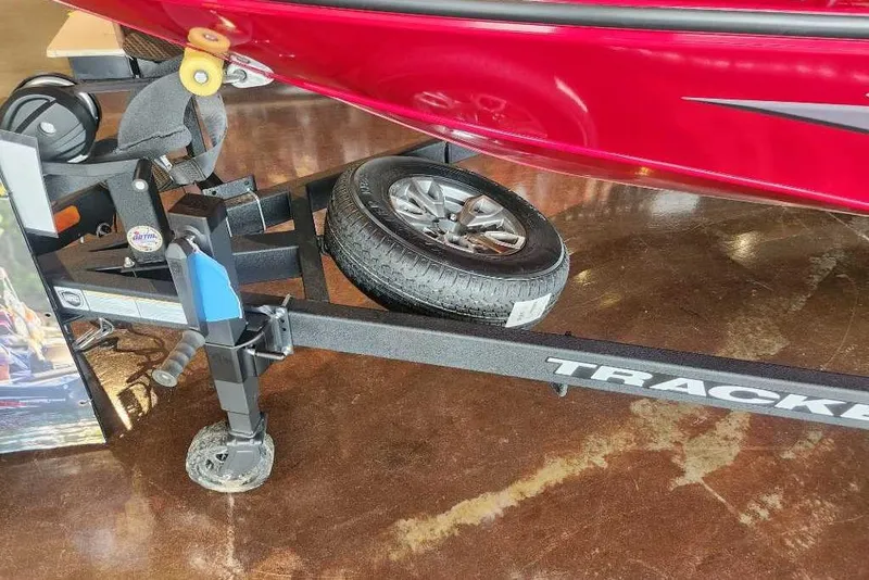 Slide: The Image of 2025 Tracker Savage 215 boat trailer with spare tire, displayed indoors. - 92