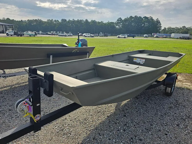 Slide: The Image of 2025 Tracker Grizzly 15 Jon boat on trailer, parked on gravel near grassy field. - 6