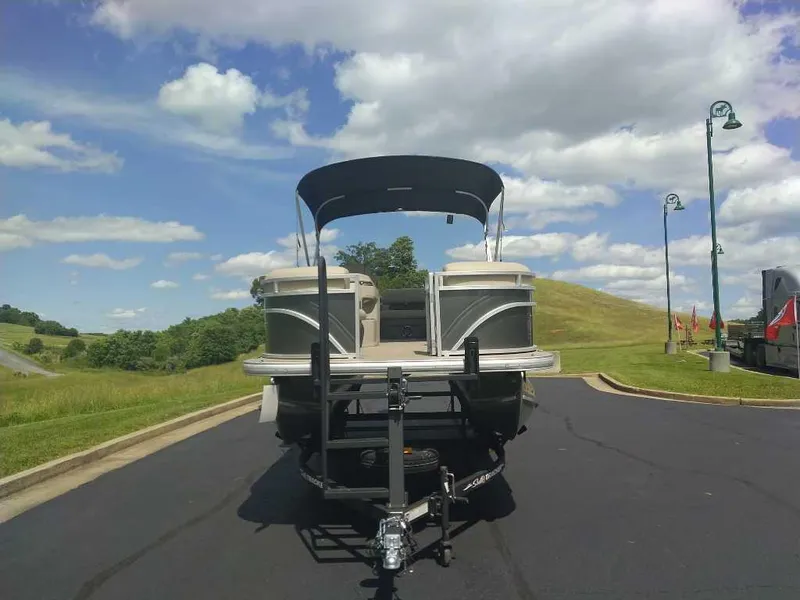 Slide: The Image of 2025 Sun Tracker Party Barge 20 DLX pontoon boat on trailer, parked on a sunny day. - 2