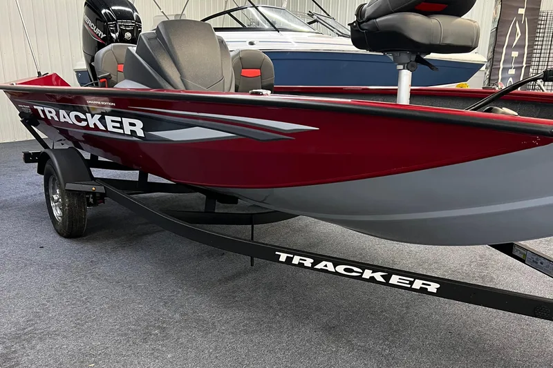 Slide: The Image of 2025 Tracker Pro Team 175 Crappie Edition boat, red and gray, on trailer in showroom. - 2