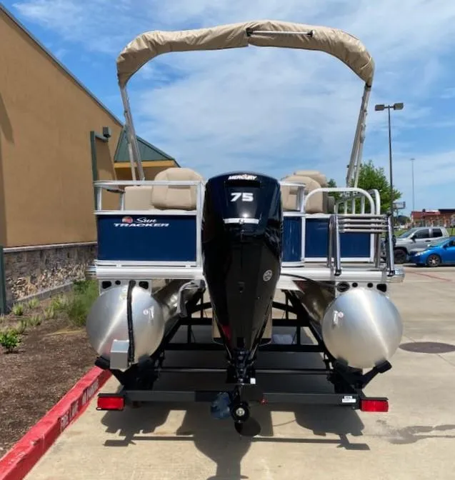 Slide: The Image of 2025 Sun Tracker Bass Buggy 18 DLX pontoon boat with 75 HP engine, parked outdoors. - 7