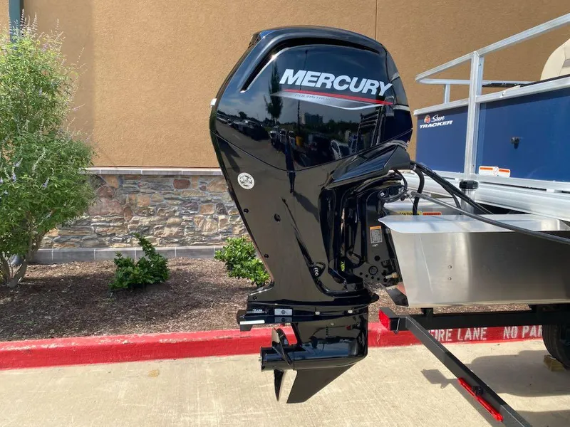 Slide: The Image of 2025 Sun Tracker Bass Buggy 18 DLX with Mercury outboard motor, parked outdoors. - 8