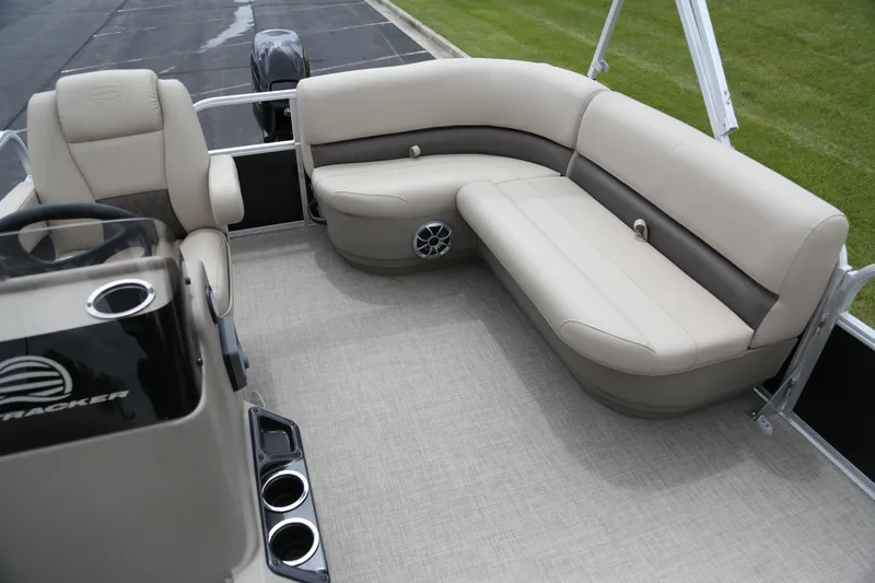 Slide: The Image of 2025 Sun Tracker Party Barge 16 DLX interior with beige seating and cup holders. - 4