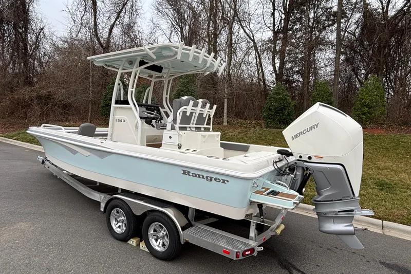 Slide: The Image of 2025 Ranger 2360 Bay boat with Mercury engine on a trailer, parked outdoors. - 4