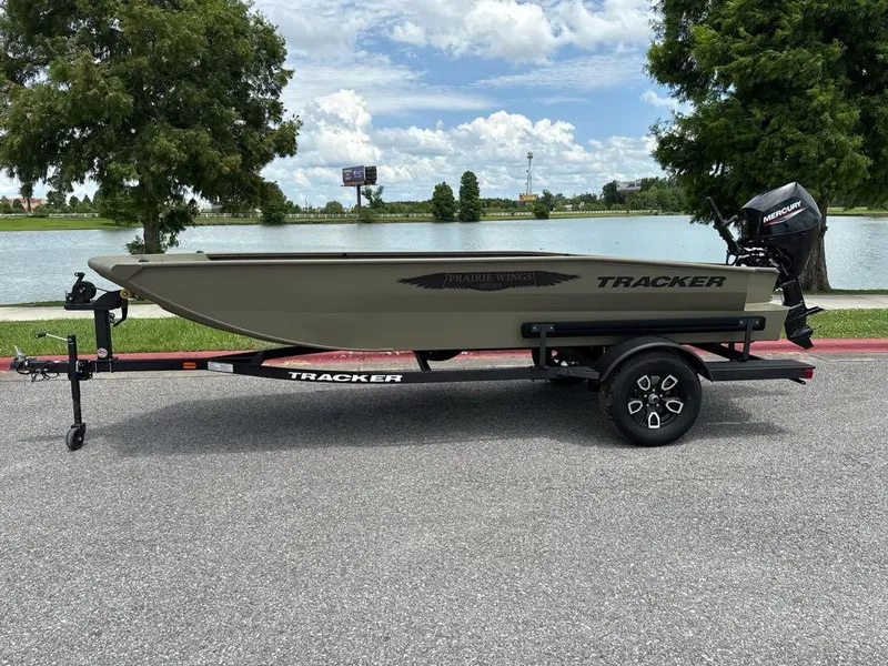 The Image of 2025 Tracker Grizzly 1650 T Prairie Wings Edition boat on trailer by a lake. - 0