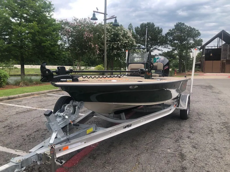 Slide: The Image of 2025 Mako 18 Pro Skiff Backwater Edition on trailer, parked outdoors near trees. - 2