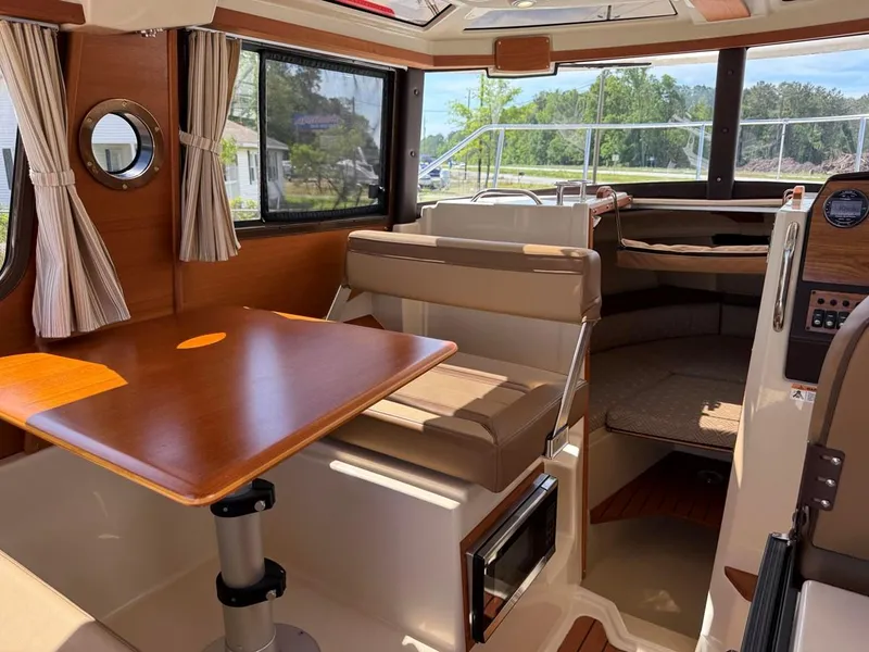 Slide: The Image of 2021 Ranger Tugs R-23 interior with dining area, seating, and windows. - 10