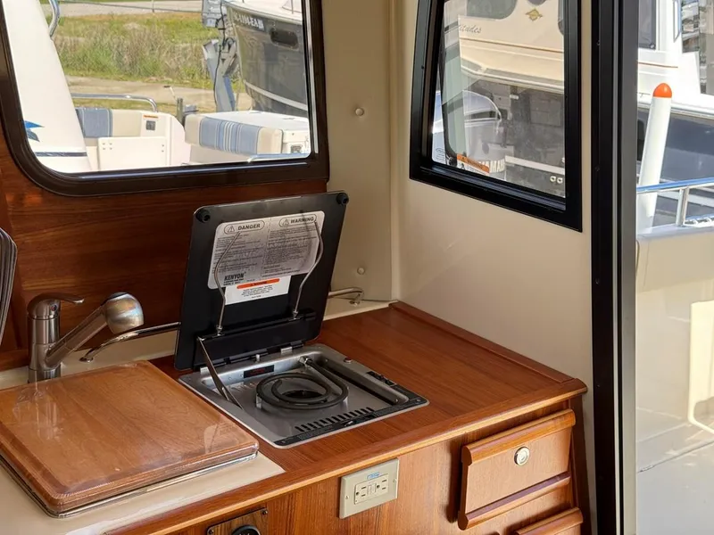 Slide: The Image of 2021 Ranger Tugs R-23 interior with compact kitchen, featuring stove and sink. - 15