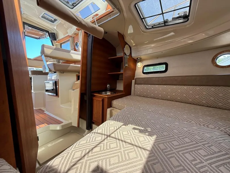 Slide: The Image of 2021 Ranger Tugs R-23 interior cabin with bed, kitchenette, and natural light. - 17