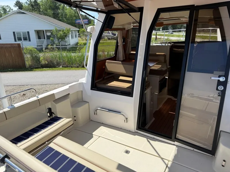 Slide: The Image of 2021 Ranger Tugs R-23 boat interior with seating and glass doors, docked near a house. - 7