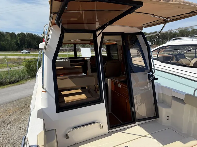 Slide: The Image of 2021 Ranger Tugs R-23 boat with open cabin door, showcasing interior seating and cabinetry. - 8