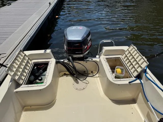 Slide: The Image of 1993 Key West 1720 DC boat with open storage compartments and outboard motor at dock. - 10