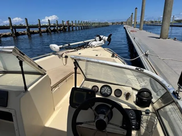 Slide: The Image of 1993 Key West 1720 DC boat docked, featuring steering console and gauges, under clear blue sky. - 12