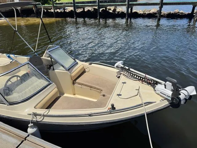 Slide: The Image of 1993 Key West 1720 DC boat docked on calm water, featuring dual consoles and a trolling motor. - 16