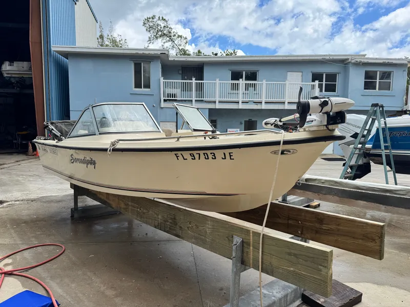 Slide: The Image of 1993 Key West 1720 DC boat on wooden supports, parked outside a blue building. - 3