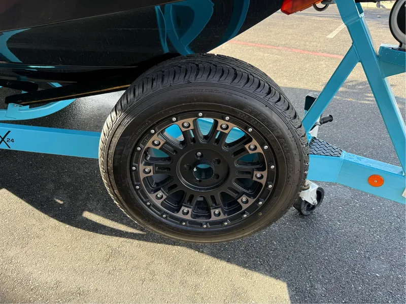 Slide: The Image of 2019 MasterCraft X24 trailer wheel with black alloy rim on asphalt. - 10