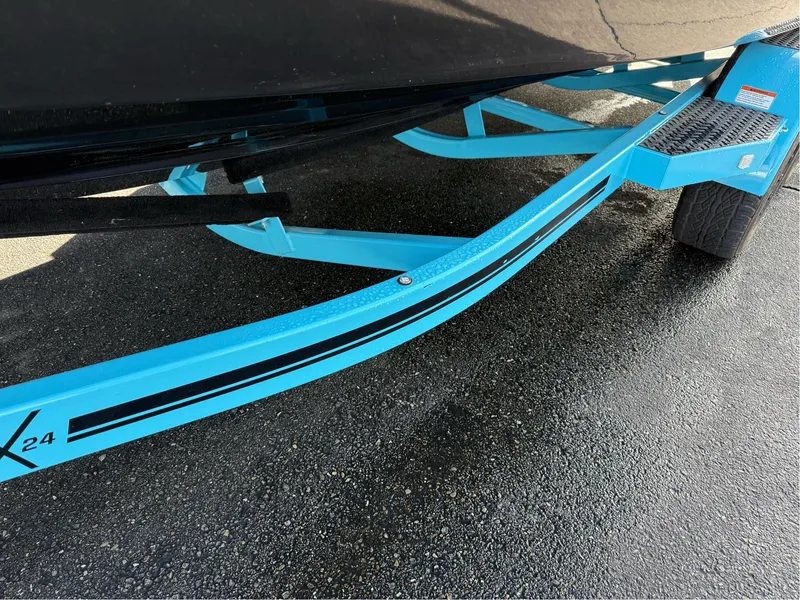 Slide: The Image of 2019 MasterCraft X24 boat trailer with blue accents on wet pavement. - 11