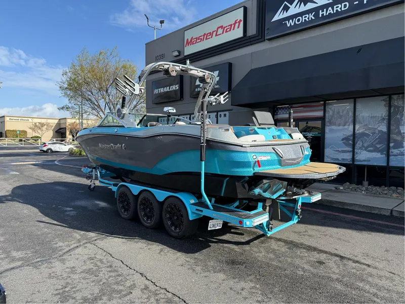Slide: The Image of 2019 MasterCraft X24 boat on trailer outside dealership, showcasing sleek design and vibrant color. - 2