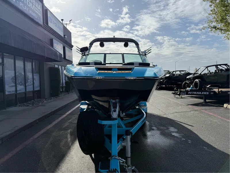 Slide: The Image of 2019 MasterCraft X24 boat on trailer, parked outdoors under a partly cloudy sky. - 6