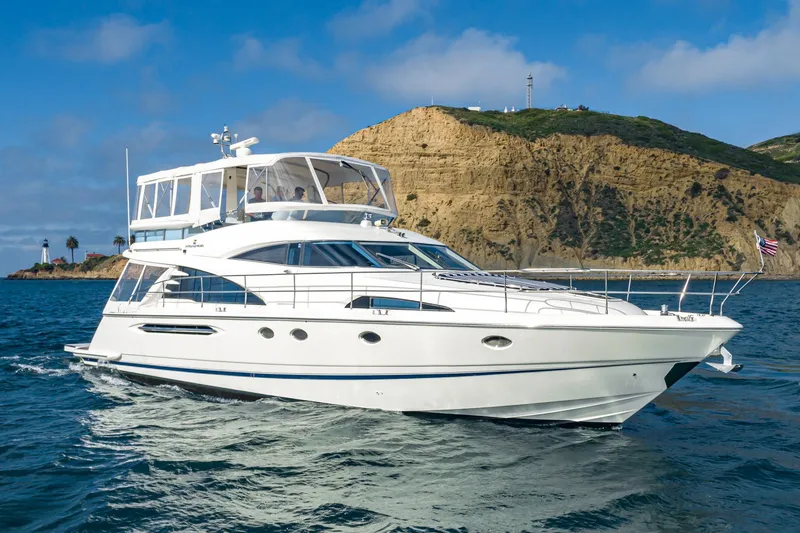 Slide: The Image of 2002 Fairline Squadron 58 yacht cruising near a rocky coastline under a clear blue sky. - 9