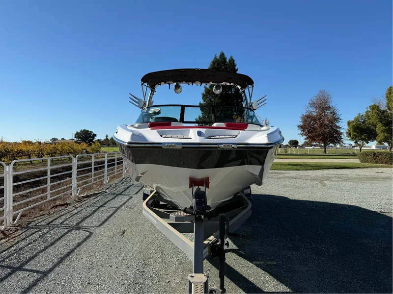 Slide: The Image of 2022 MasterCraft XT24 boat on trailer, parked outdoors under clear blue sky. - 2