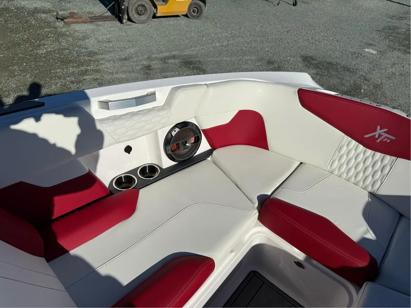 Slide: The Image of 2022 MasterCraft XT24 boat interior with red and white seating, cup holders, and speaker. - 22
