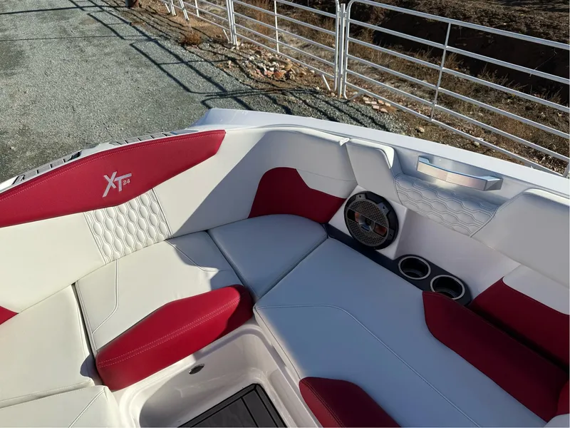 Slide: The Image of 2022 MasterCraft XT24 boat interior with red and white seating, speaker, and cup holders. - 24