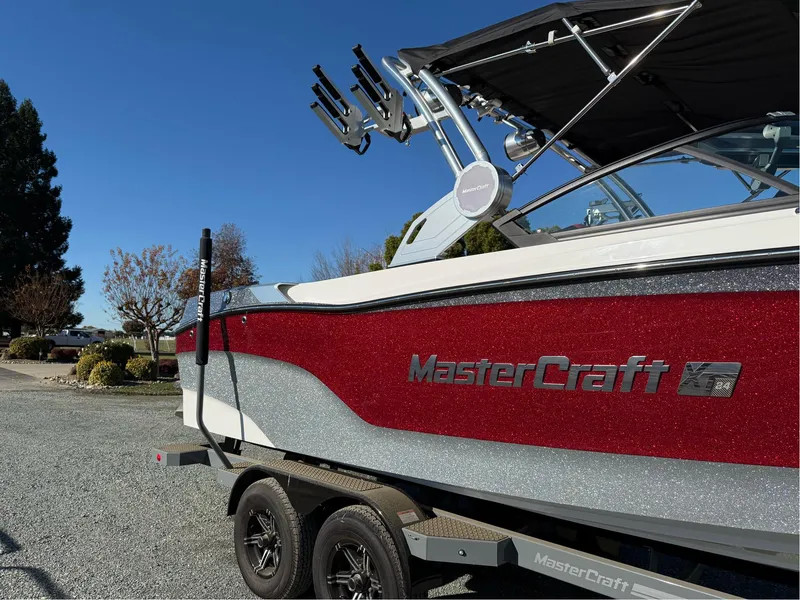 Slide: The Image of 2022 MasterCraft XT24 boat on trailer, red and silver design, parked outdoors. - 4