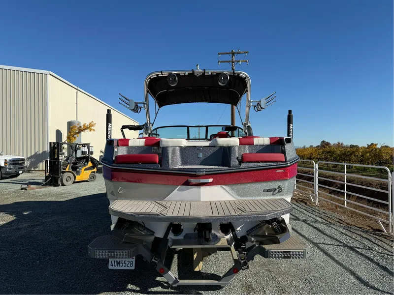 Slide: The Image of 2022 MasterCraft XT24 boat parked outdoors, rear view with red and white detailing. - 6