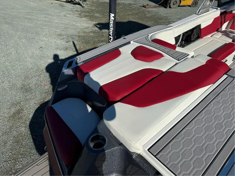 Slide: The Image of 2022 MasterCraft XT24 boat with red and white seating, docked outdoors. - 8