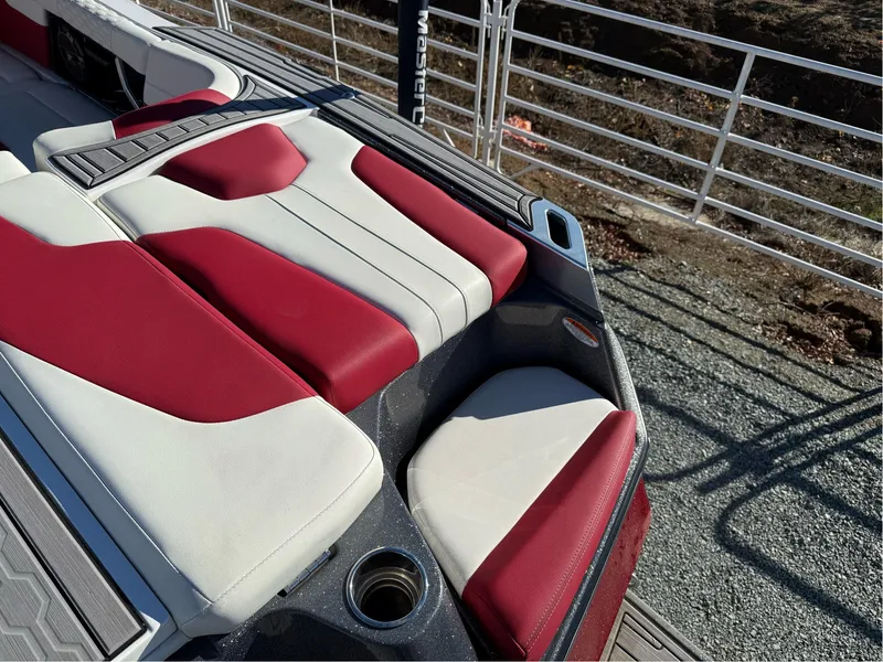 Slide: The Image of 2022 MasterCraft XT24 boat interior with red and white seating, cup holder, and sleek design. - 9
