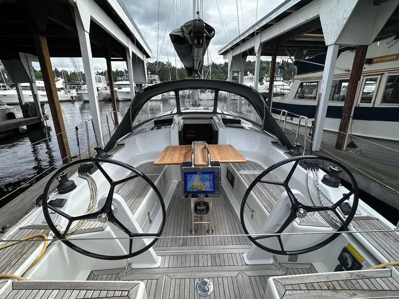 Slide: The Image of 2019 Hanse 348 yacht cockpit with dual steering wheels and navigation system, docked at marina. - 14