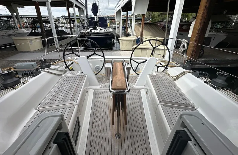 Slide: The Image of 2019 Hanse 348 yacht cockpit with dual steering wheels, docked at a marina. - 16