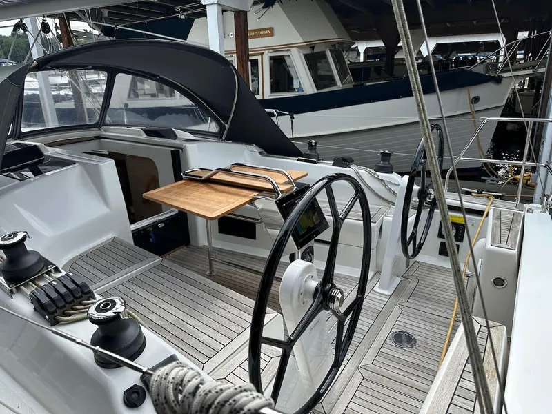 Slide: The Image of 2019 Hanse 348 yacht cockpit with dual steering wheels and wooden table, docked at marina. - 20