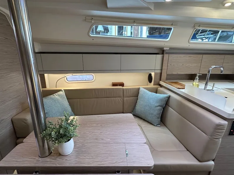 Slide: The Image of 2019 Hanse 348 yacht interior with cozy seating, table, and modern kitchen area. - 44